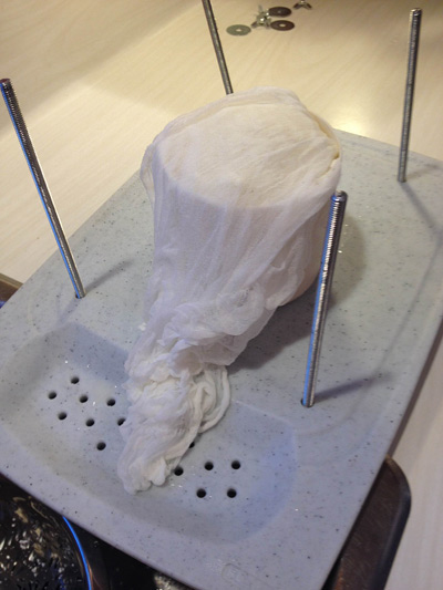 The butter muslin fabric is folded over the top of the curds. I fold it toward the sink because whey will wick down the fabric. Learned that one the hard way!